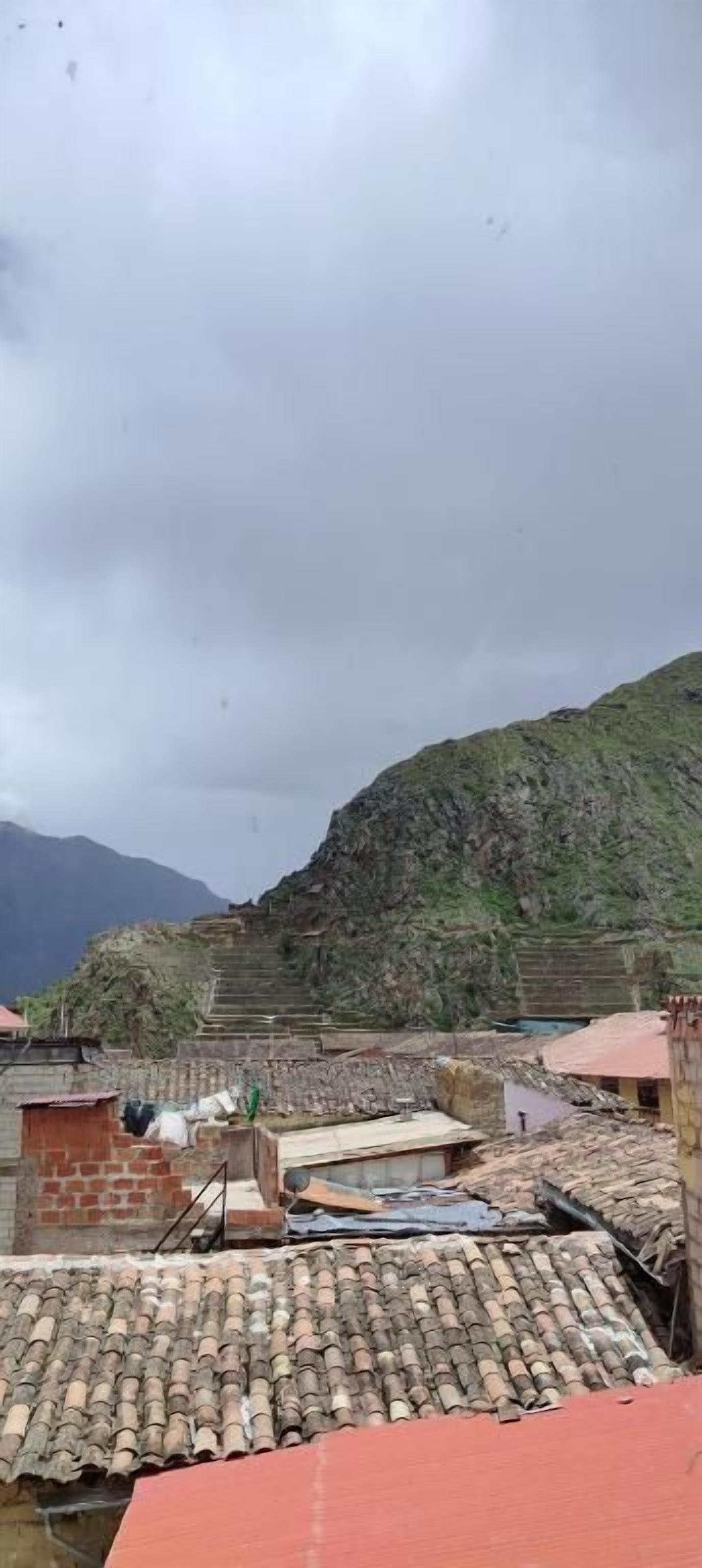 A terraced building with a flat roof, surrounded by a mountainous landscape.