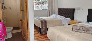 Une chambre d’hôtel avec deux lits, une porte en bois, une douche et une vue sur l’extérieur.