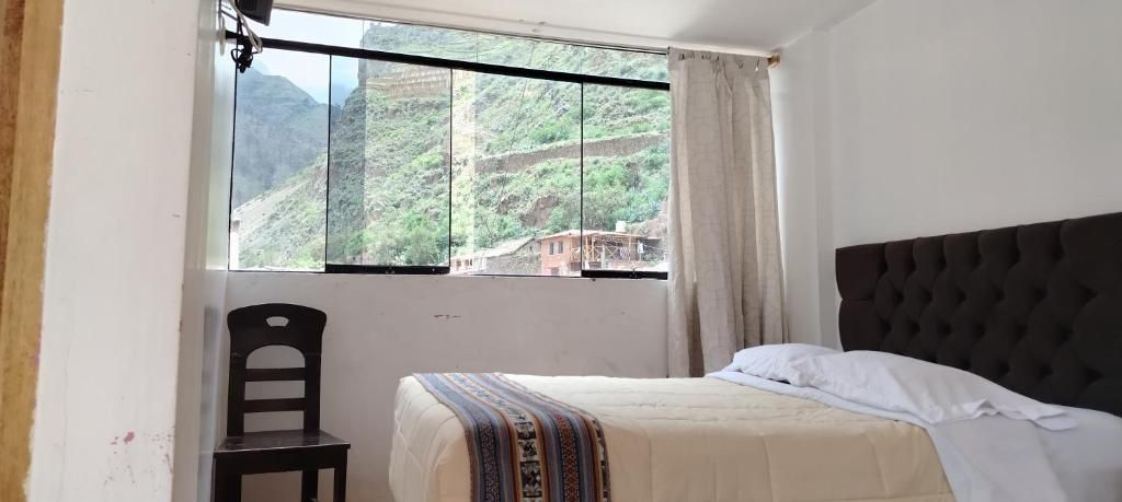 A room with a bed, a chair, and a window with a view of a mountainous landscape.