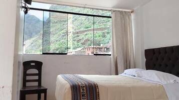 Une chambre avec un lit, une chaise et une fenêtre donnant sur un paysage montagneux.