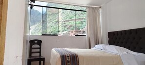 Une chambre avec un lit, une chaise et une fenêtre donnant sur un paysage montagneux.