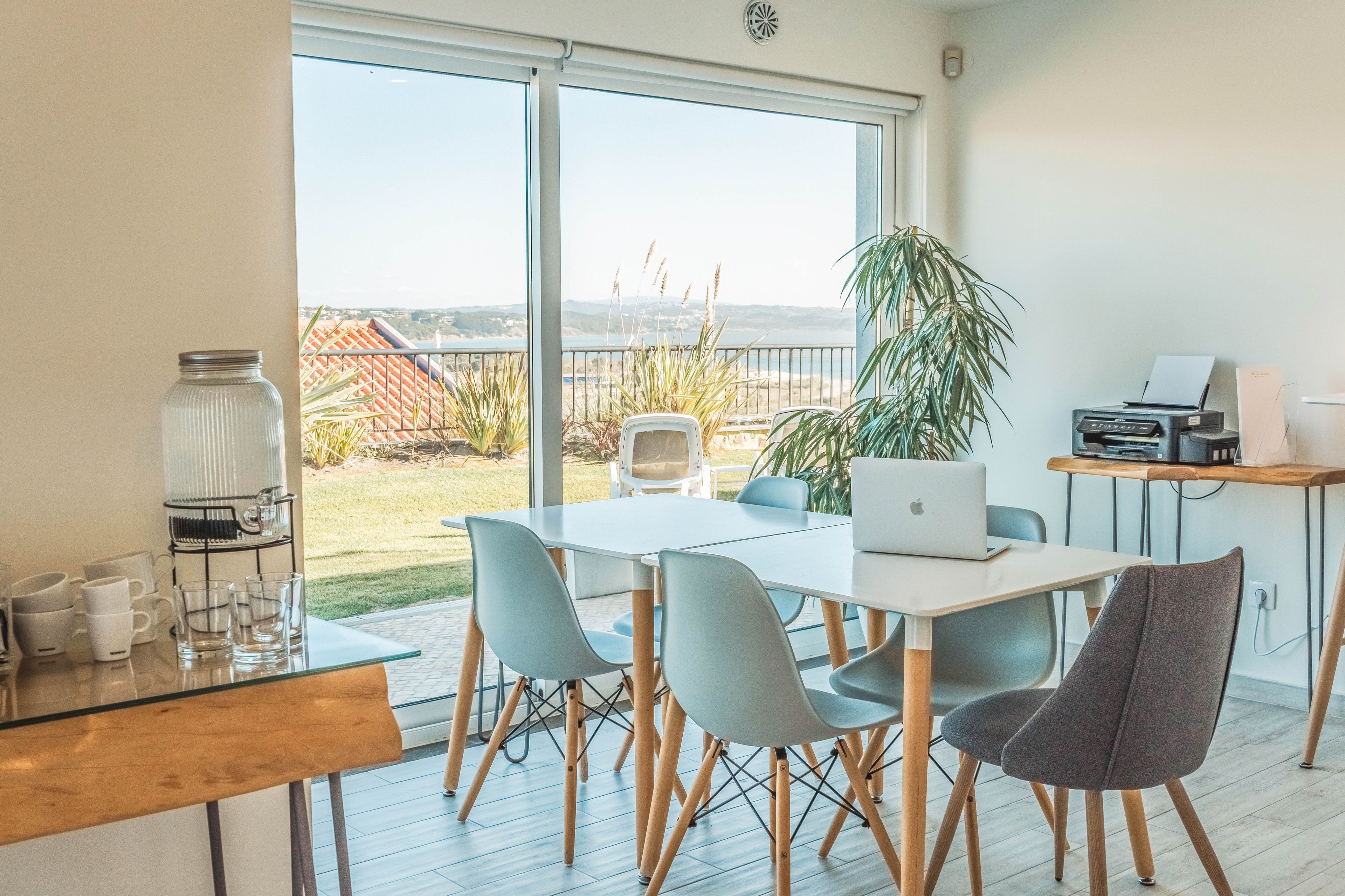 Espaço de escritório moderno com uma grande janela com vista para um jardim e para o mar.