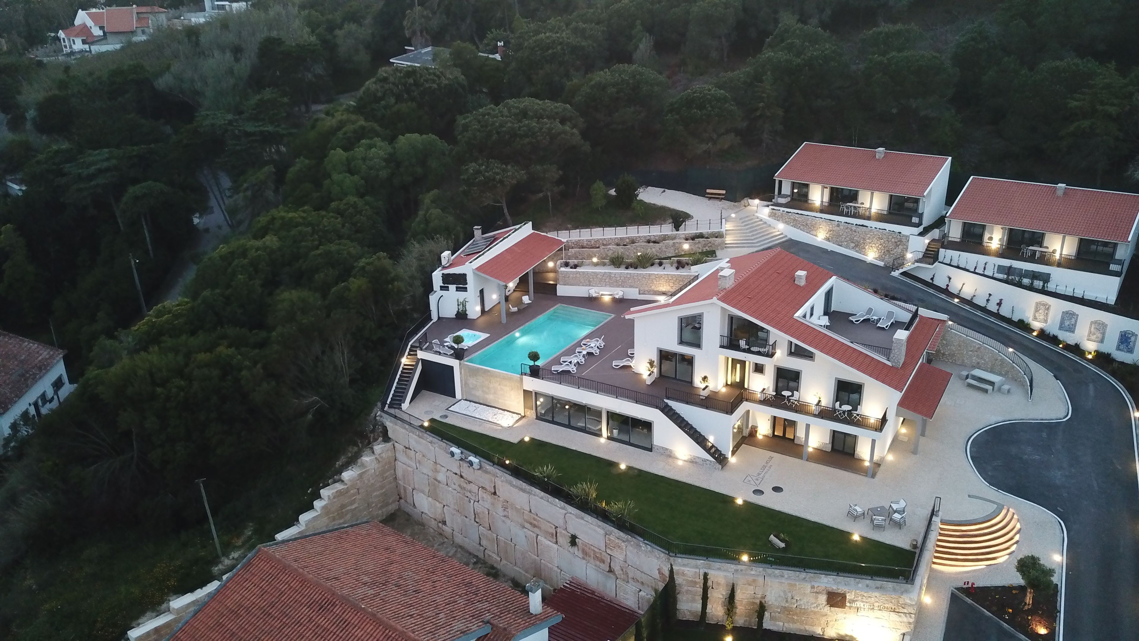 A modern villa with a swimming pool, multiple balconies, and a stone retaining wall.