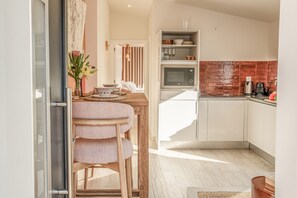 Uma cozinha moderna com área de refeições, com uma mesa de madeira, cadeiras e um vaso de flores.