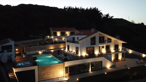 Uma casa moderna de dois andares com piscina, área de estar externa e fachada de pedra.