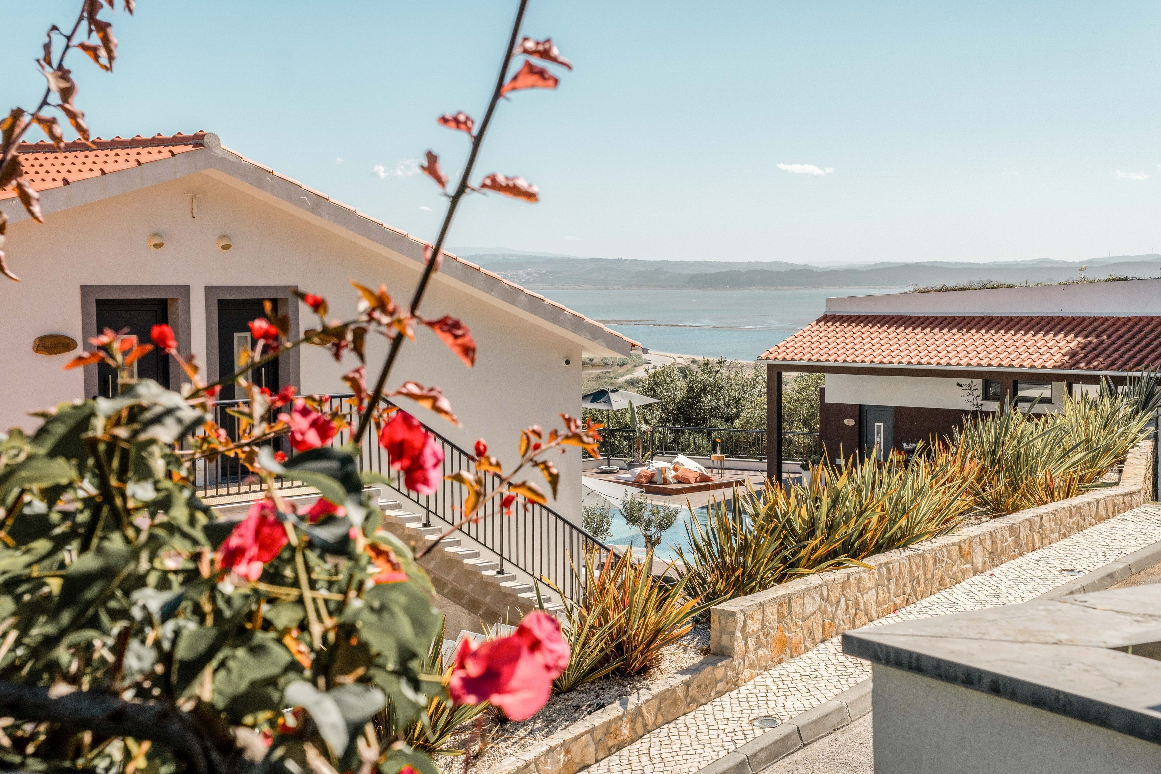 A modern building with a pool, a view of the sea, and a stone pathway.
