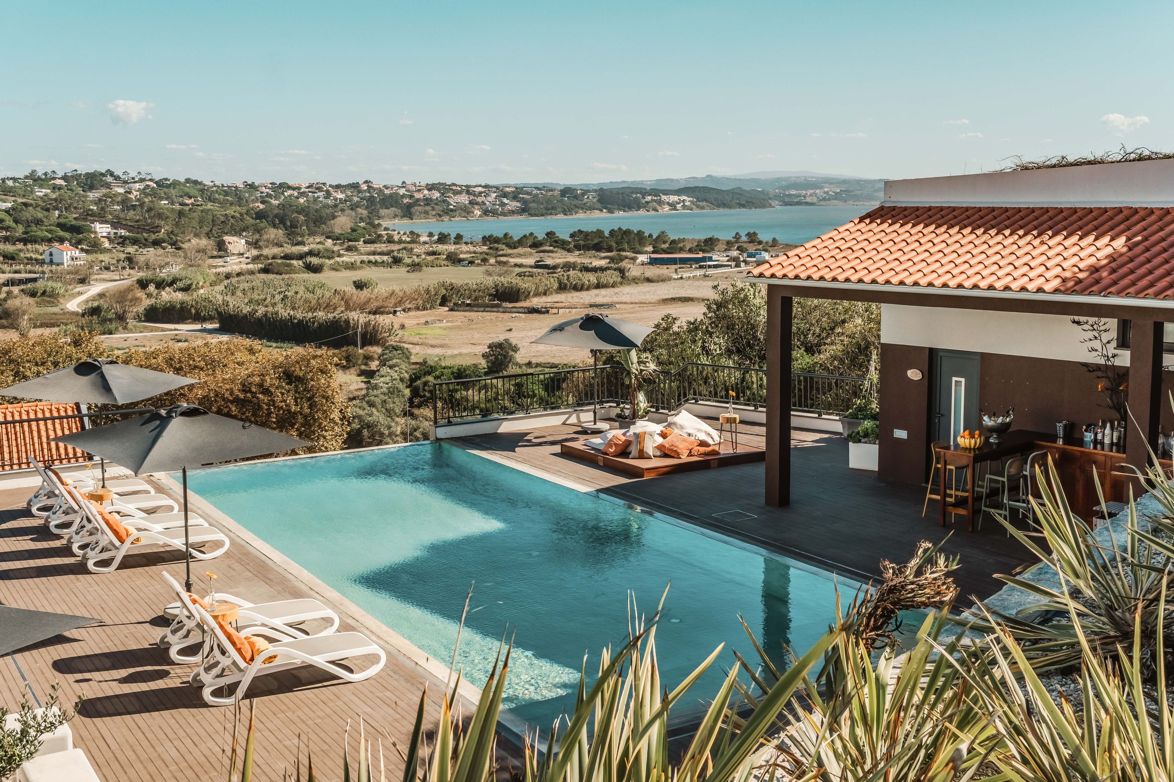 A swimming pool with lounge chairs and a view of a coastal landscape.