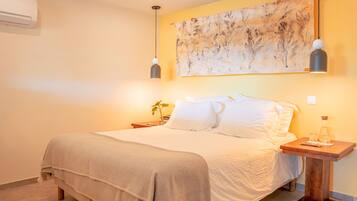 A hotel room with a bed, a nightstand, a wall-mounted air conditioner, and a painting.