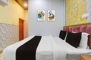A hotel room with a bed, a wall-mounted air conditioner, and two framed artworks. - Super Hotel O Banaras Junction BLW (Varanasi)