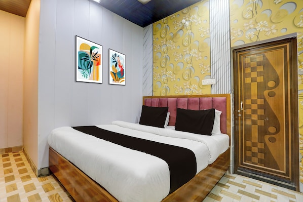 A bedroom with a bed, a wooden door, and two framed artworks on the wall. - Super Hotel O Banaras Junction BLW (Varanasi)