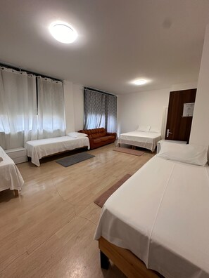 A hotel room with two single beds, a sofa, and a window with curtains. - New Listing (Venezia)