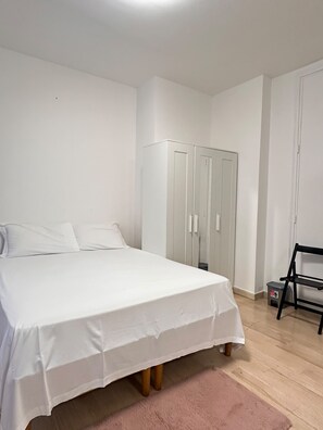 A bedroom with a bed, a wardrobe, and a chair. - New Listing (Venezia)