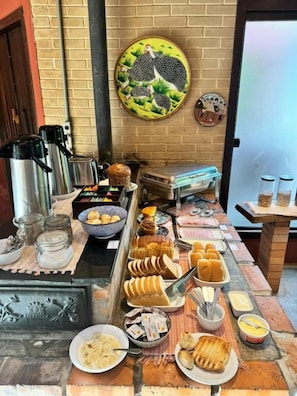A buffet setup with various food items and condiments. - Pousada Guata Porã  (Foz do Iguaçu)