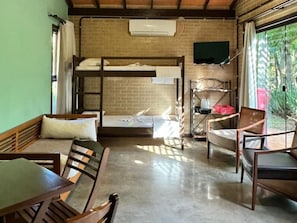 A bunk bed with a flat-screen TV above it, a dining table with chairs, and a window with curtains. - Pousada Guata Porã  (Foz do Iguaçu)