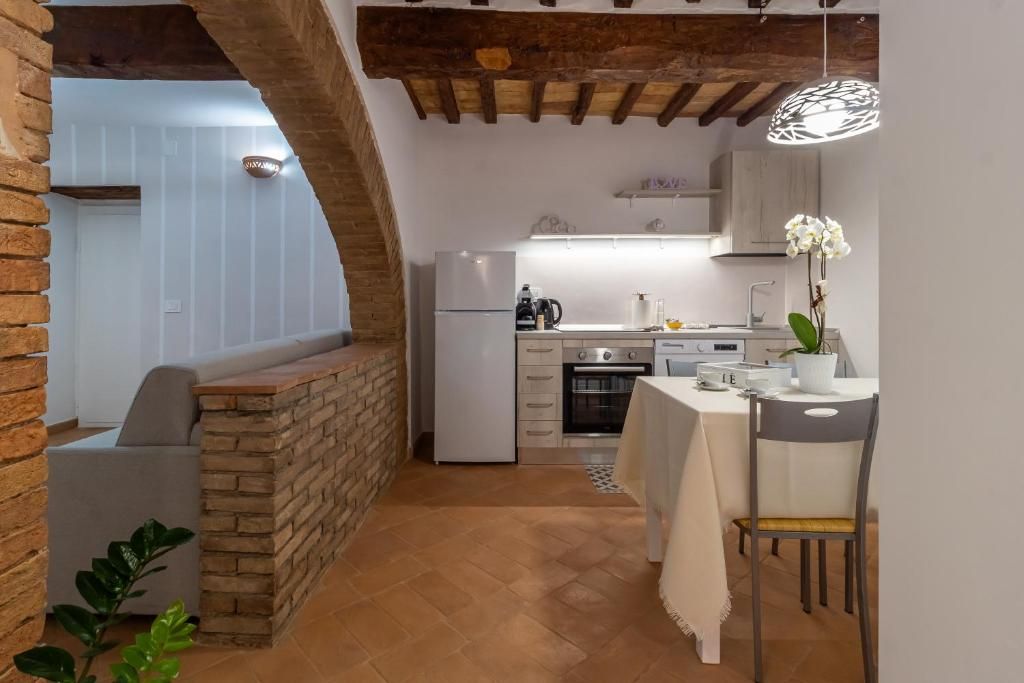 A kitchen with a brick wall, a dining table with chairs, and a hanging pendant light.