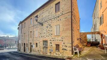 A stone building with multiple windows and a small outdoor seating area.