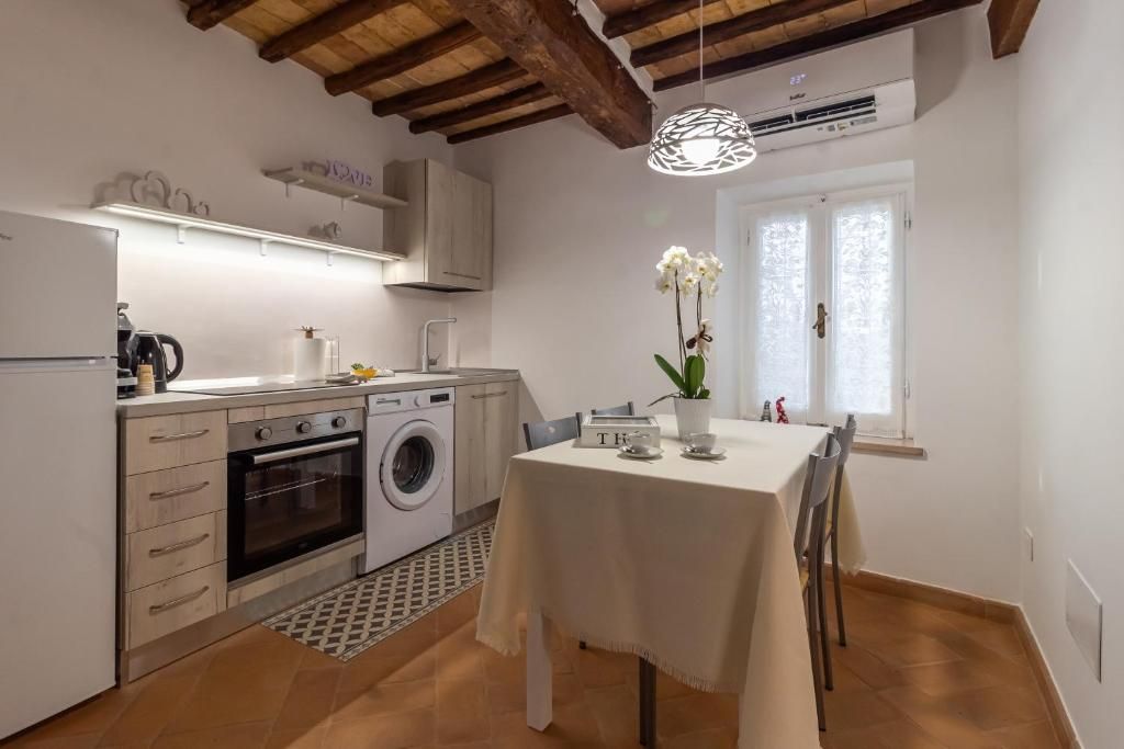 A kitchen with a washing machine, oven, and a dining table with chairs.