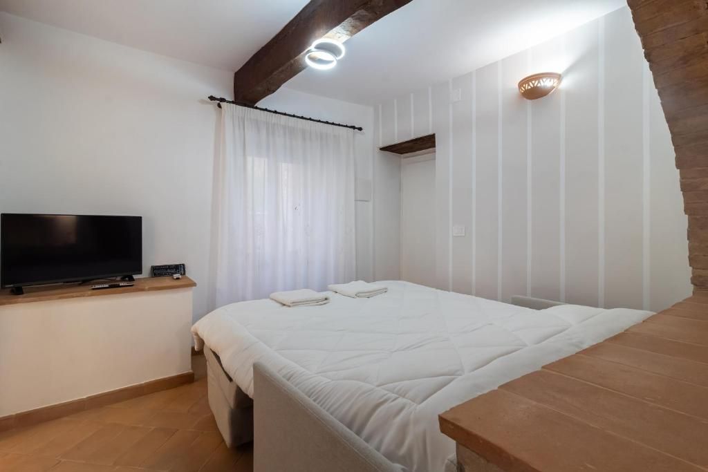 Ein Hotelzimmer mit einem Bett, einem Flachbildfernseher, einer hölzernen Bank und einer Backsteinwand.