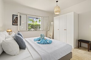 Une chambre à coucher comprenant un lit, une lampe de chevet, une armoire et une fenêtre donnant sur un paysage verdoyant.