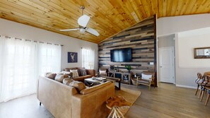 Un salon comprenant un canapé, une table basse et un téléviseur fixé à un mur en bois.