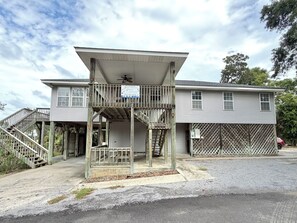 A two-story building with a covered porch, a staircase, and a fenced area. - Edisto 3BR Home~ Walk to Beach (Edisto Island)