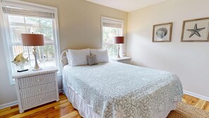 A bedroom with a bed, two nightstands, a lamp, a fish decoration, and framed pictures on the wall. - Edisto 3BR Home~ Walk to Beach (Edisto Island)