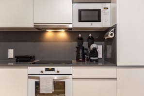 Eine moderne Küche mit Backofen von Bosch, einer Mikrowelle, einer Kaffeemaschine und einem Wasserkocher.