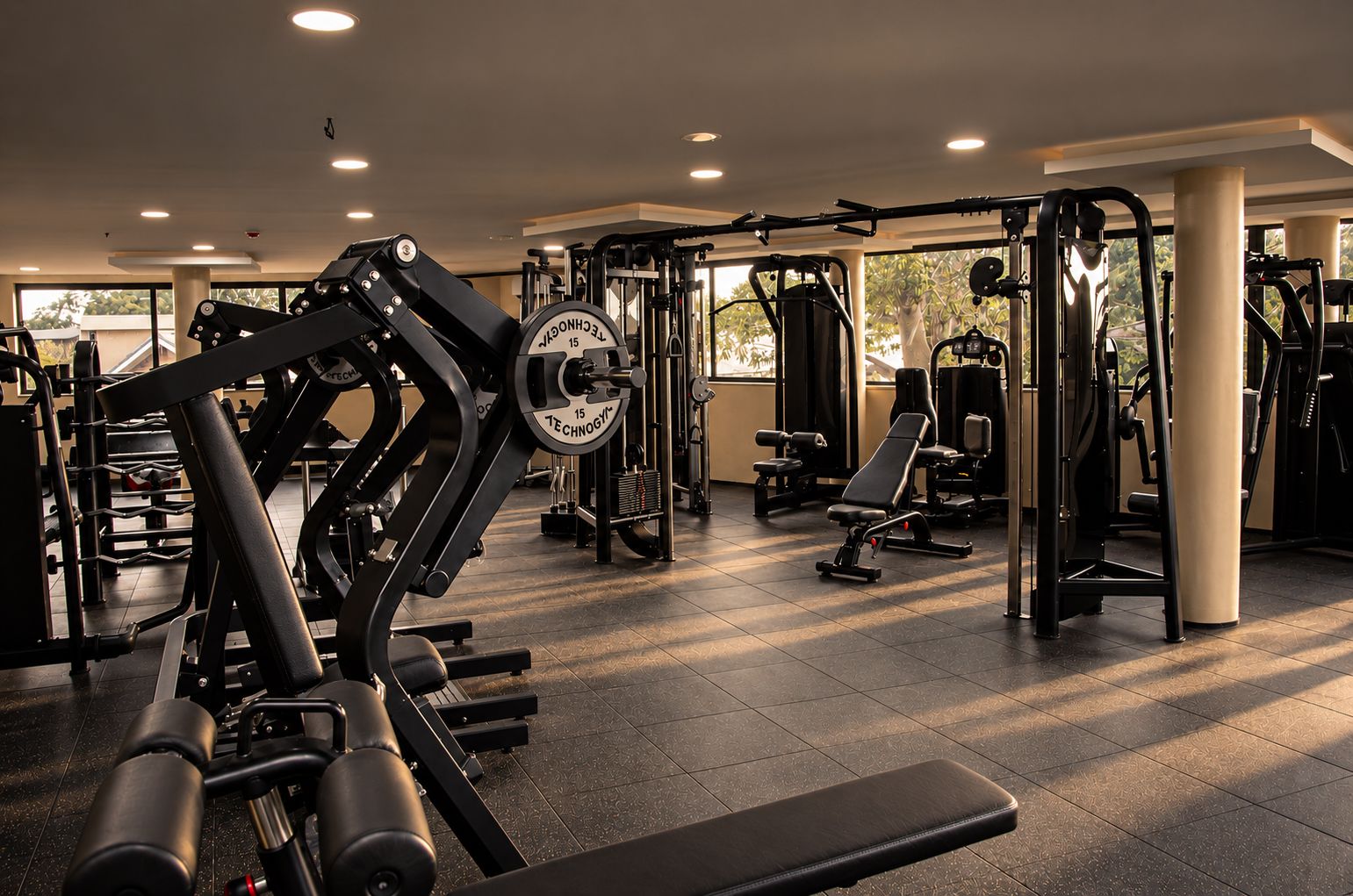 A gym with various exercise equipment, including weight machines and free weights, and a bench.