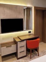 Un escritorio moderno con un televisor de pantalla plana, una ventana con cortinas y una silla.