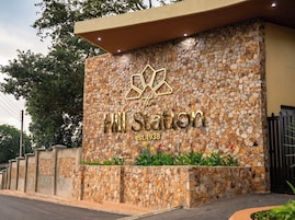 Entrada de un hotel con fachada de piedra y un logo sobre el nombre 'Hill Station', fundado en 1938.