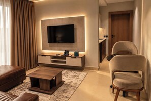 A modern living room with a flat-screen TV, a wooden coffee table, a sofa, and a chair.