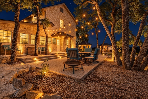 A stone house with a patio area, outdoor seating, and string lights.