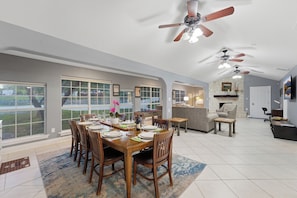 A spacious dining area with a large table set for a meal, a kitchen area with a stone fireplace, and a living room with a fireplace and seating.
