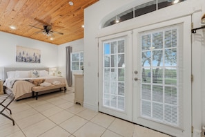 A bedroom with a bed, a ceiling fan, a painting, and a window with blinds.