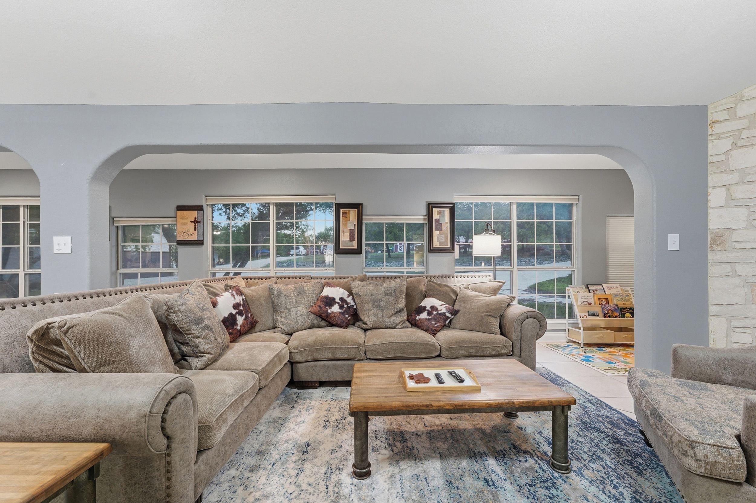 A living room with a sectional sofa, a coffee table, and a stone wall.