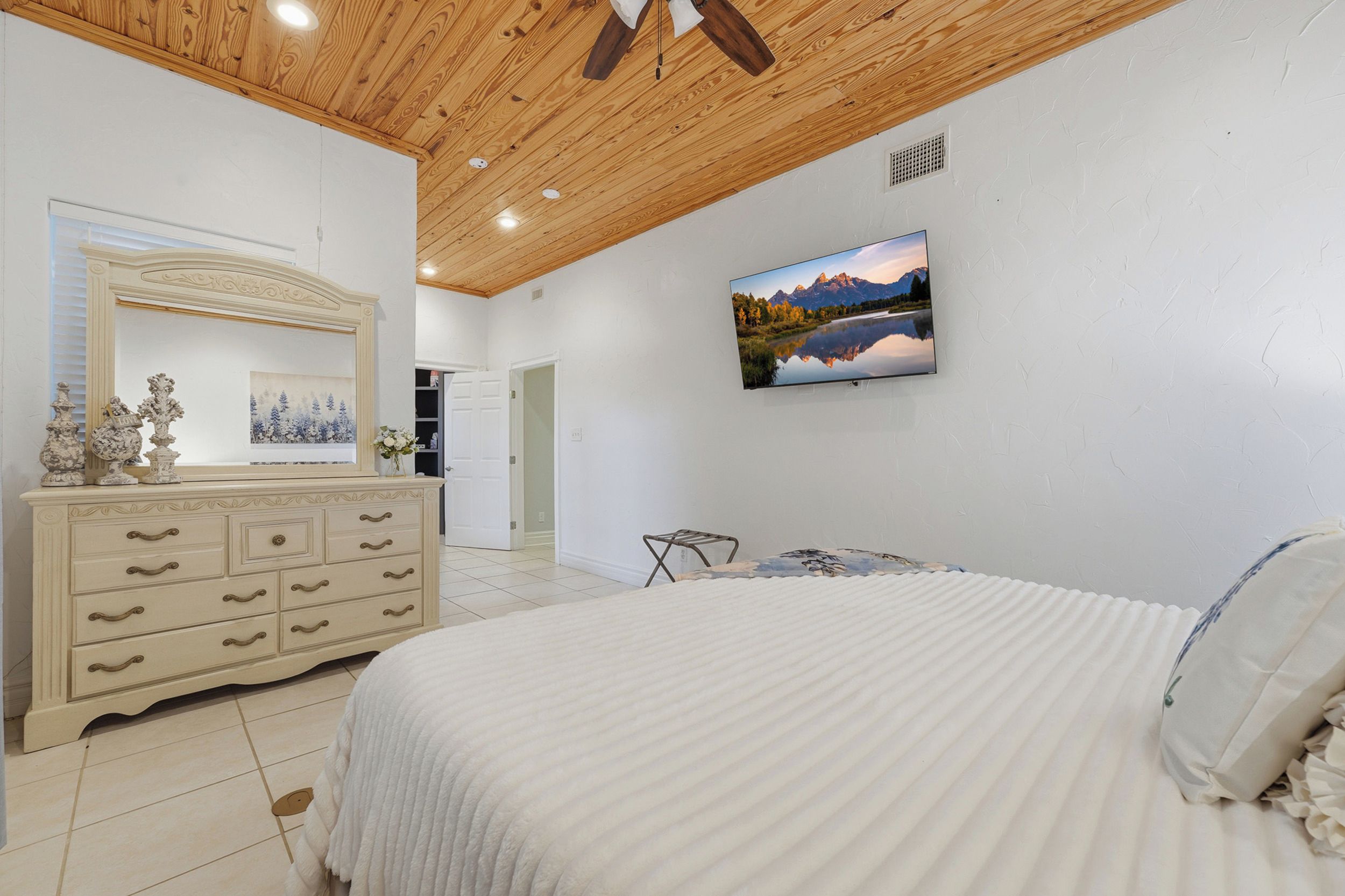Een slaapkamer met een bed, een dressoir en een televisie aan de muur.
