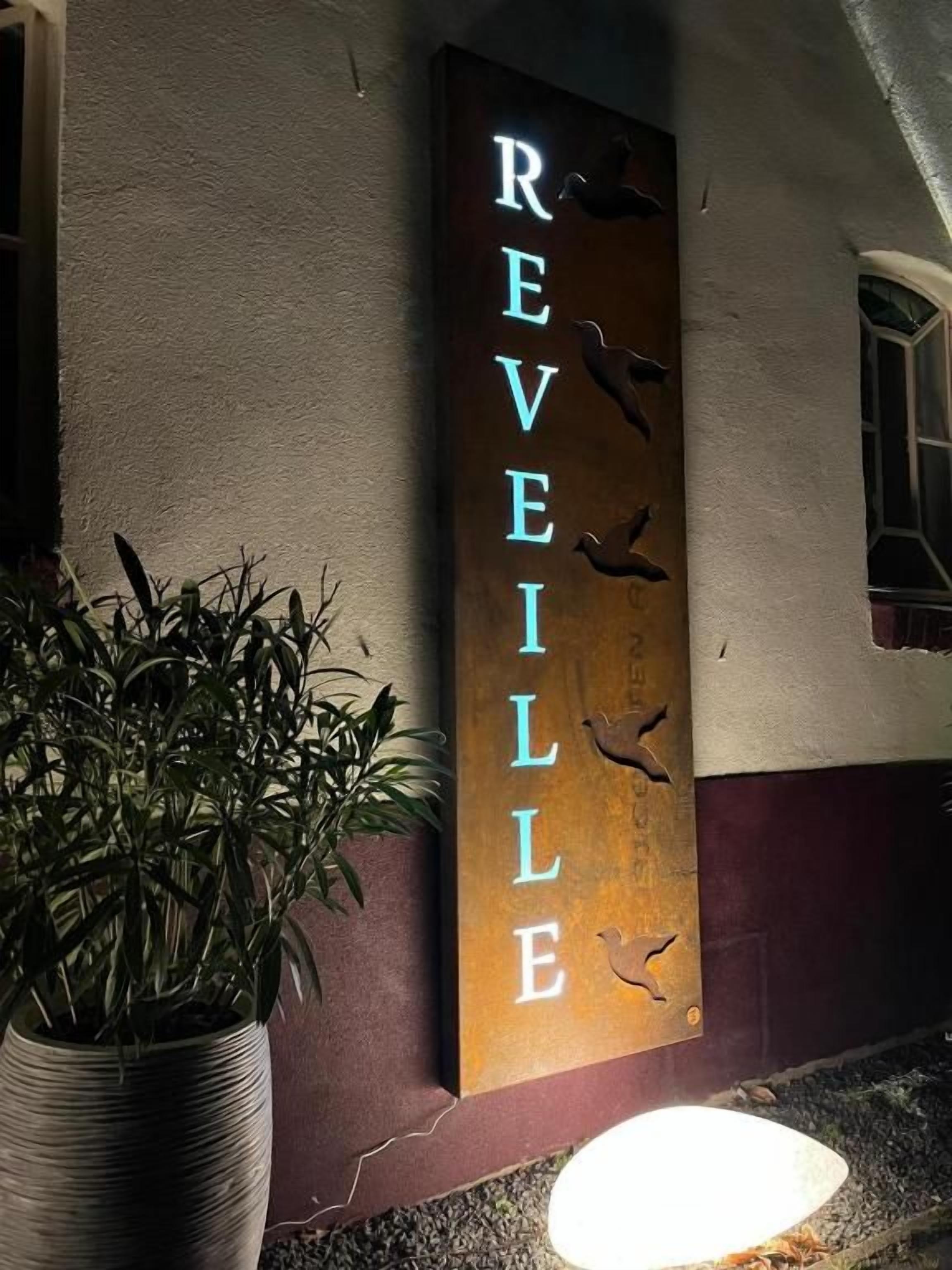 Un letrero vertical con la palabra 'REVELLE' y siluetas de pájaros.