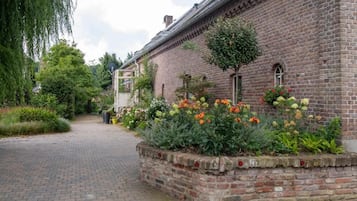 Un edificio de ladrillo con un sendero pavimentado y un parterre con diversas plantas y flores.