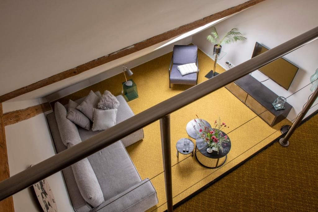 Una habitación con techos altos, un sofá, una mesa pequeña con un florero y una silla.