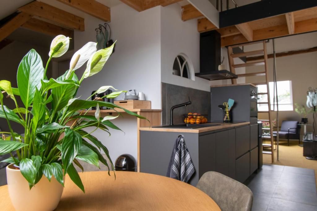 Una cocina moderna con una isla central, un comedor con una mesa redonda y una escalera que lleva a un nivel superior.