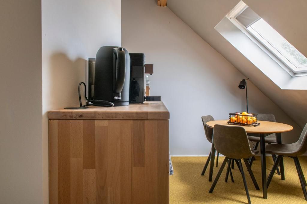 Ein Zimmer mit einem Holzschrank, einer Kaffeemaschine, einem Tisch mit Stühlen und einem Oberlicht.