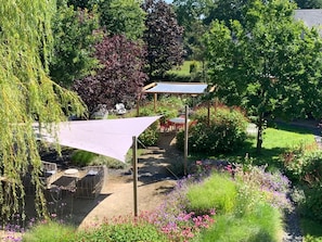 Un jardín con un pérgola, una zona de estar y diversas plantas.