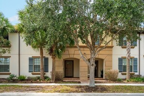 A residential building with a symmetrical facade, a central entrance with a door, and a small porch area. - 5BR townhome near Disney | Pool, by clubhouse (Kissimmee)