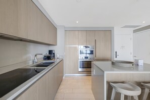 Uma cozinha moderna com ilha central, eletrodomésticos de aço inoxidável e armários de madeira clara.