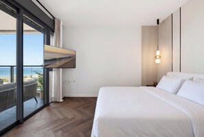 Habitación de hotel con una cama grande, vista al mar y una lámpara moderna.