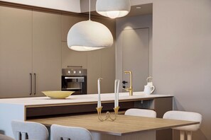 A modern kitchen with a central island, pendant lighting, and a dining area with chairs. - Luxury Coastal Escape in Achziv with Sea Views (Nahariya)