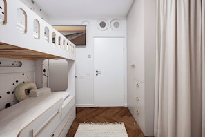 A room with a bunk bed, a door, a wall-mounted TV, and a patterned rug. - Premium 6BR Coastal Stay in Achziv by SeaNRent (Nahariya)