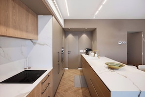 A modern kitchen with a built-in stove, wooden cabinets, and a marble countertop. - Premium 6BR Coastal Stay in Achziv by SeaNRent (Nahariya)