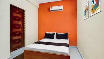 Habitación de hotel con cama, equipo de aire acondicionado, una puerta y una pared decorada con marcos.