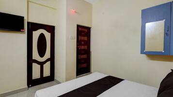 Una habitación de hotel con una cama, un televisor montado en la pared y una puerta con diseño decorativo.
